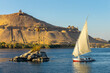 Felucca (traditinal egyptian sailing boat) on the Nile river and the Dome of Abu Al-Hawa (Qubbet el-Hawa) or Dome of the Wind in Aswan, Egypt