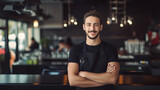 Fototapeta  - Portrait of a man barista in black t-shirt and apron behind counter in cafe.

