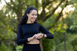© Liubomir - A smiling woman in sportswear checks her fitness tracker during an outdoor workout session in a lush park at sunset.