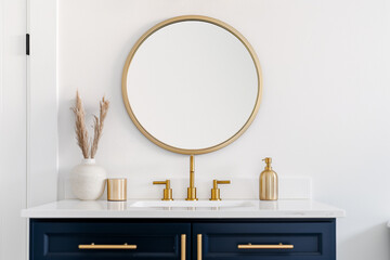 A bathroom detail with a gold mirror and faucet, blue vanity cabinet, and decorations on the white countertop.