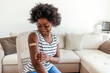 © Jelena Stanojkovic - Portrait of a young African American woman wearing a bandaid after getting vaccinated. Smiling black woman looking positive about getting the vaccine and posing against a bright background.