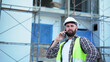 Senior architect or civil engineer talking to phone pointing finger to inspection and control at construction site. building project