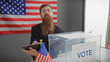A bearded man with glasses noting beside a ballot box with an american flag background in a voting station.