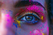 Primer plano de un ojo azul y parte de la cara de una mujer  pintada con con polvo holi de colores, concepto fiesta holi india