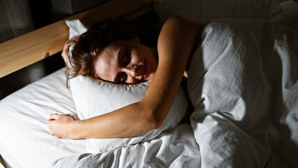 Poster - A serene young woman in peaceful slumber, enveloped by soft bedding in a cozy bedroom setting