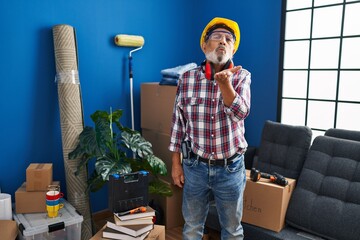 Canvas Print - Cheeky senior man in hardhat and safety glasses blowing a love-filled kiss to the camera in his new home - a flirtatious handyman with a sparkle in his eye.