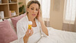 © Krakenimages.com - Young blonde woman holding pills bottle suffering for headache sitting on bed at bedroom