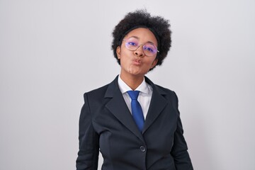 Wall Mural - Beautiful african woman with curly hair wearing business jacket and glasses looking at the camera blowing a kiss on air being lovely and sexy. love expression.