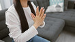 © Krakenimages.com - A young asian woman in a white shirt clapping her hands in a well-lit living room