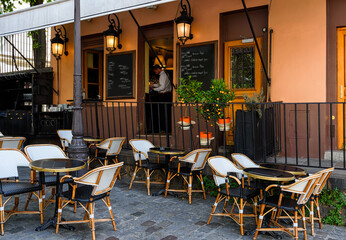 Wall Mural - Cozy street with tables of cafe in quarter Montmartre in Paris, France. Architecture and landmarks of Paris. Postcard of Paris