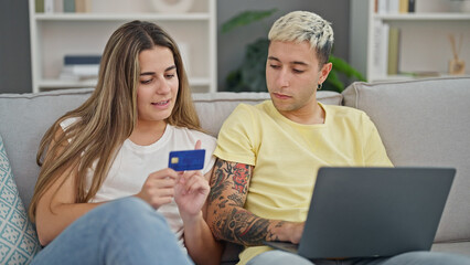 Wall Mural - Beautiful couple shopping with laptop and credit card sitting on sofa at home