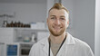 © Krakenimages.com - Handsome young man with beard smiling in white lab coat at a modern clinic