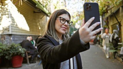 Wall Mural - A young brunette woman takes a selfie on an urban istanbul street, showcasing travel and city life.