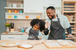 © chokniti - In a home kitchen, black father and his daughter bond over cooking a meal food, their laughter and love filling the air, embodying the joy of African American family life, Father's Day concept