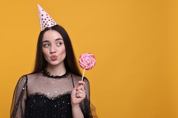 Poster - Woman in party hat holding lollipop on orange background, space for text