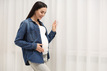 Sticker - Happy pregnant woman near window indoors, space for text