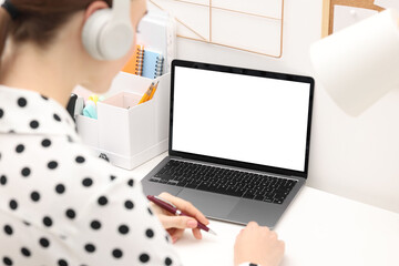 Wall Mural - E-learning. Young woman taking notes during online lesson at table indoors, closeup