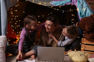 Canvas Print - Mother and her children with laptop in play tent at home