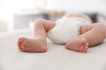 Poster - Cute little baby in diaper lying on bed in room, closeup