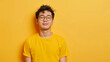 © Vizuarna - Attractive asian man wearing yellow tshirt and glasses. Isolated on yellow background.