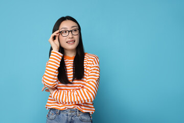 Canvas Print - Portrait of happy woman in glasses on light blue background. Space for text