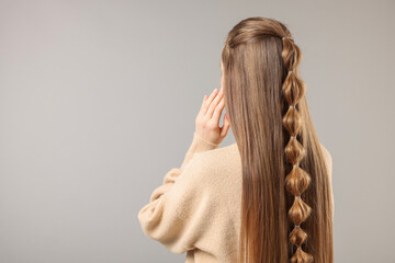 Woman with braided hair on grey background, back view. Space for text