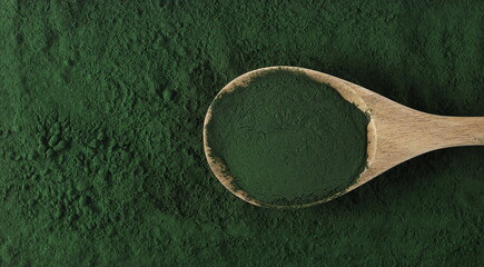 Wall Mural - Organic spirulina powder in wooden spoon background and texture, top view