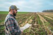 © evgenia_lo - Thoughtful farmer in plaid shirt and cap pondering future of crops in vast field, challenges of modern farming on horizon
