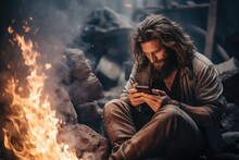 A Man Sitting In Front Of A Fire Using A Cell Phone