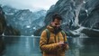 Man using smartphone by mountain lake in autumn. Travel and technology concept. Warm outdoor gear for hiking and adventure.