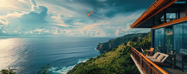 Modern cliffside villa overlooks the ocean with a paraglider soaring by, signifying luxury living and adventure.