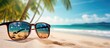 Sunglasses on sand with palm trees in background