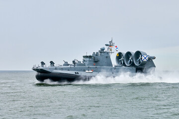 Hovercraft warship armed with armament sails into sea toward military target to attack and destroy enemy, military hovercraft ship performing strategic maneuver, Russian sea power deployment