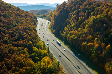 Wall Mural - View from above of I-40 freeway route in North Carolina leading to Asheville thru Appalachian mountains with yellow fall woods and fast moving trucks and cars. Interstate transportation concept