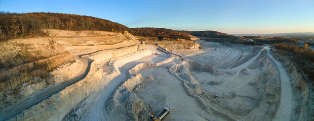 Wall Mural - Aerial view of open pit mine of sandstone materials for construction industry with excavators and dump trucks. Heavy equipment in mining and production of useful minerals concept