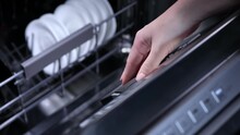 Close-up of woman hand of puting blue detergent capsule into the dishwasher.