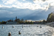 Schwäne schwimmen auf dem See an einem sonnigen Frühlingstag mit Steigenberger Inselhotel und Münster und Rheinbrücke im Hintergrund. Konstanz, Bodensee, Baden-Württemberg, Deutschland, Europa.