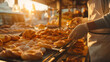 A bakery staff member taking a fresh batch of pastries out of the oven, offering samples to customers, the golden light of morning accentuating the warmth and deliciousness, natura
