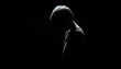  The silhouette of a sad little boy, his shoulders slumped and head bowed, against a deep black background