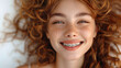 Portrait of a girl 16 years old wearing braces with glowing curly red hair. She is smiling sweetly with braces.

