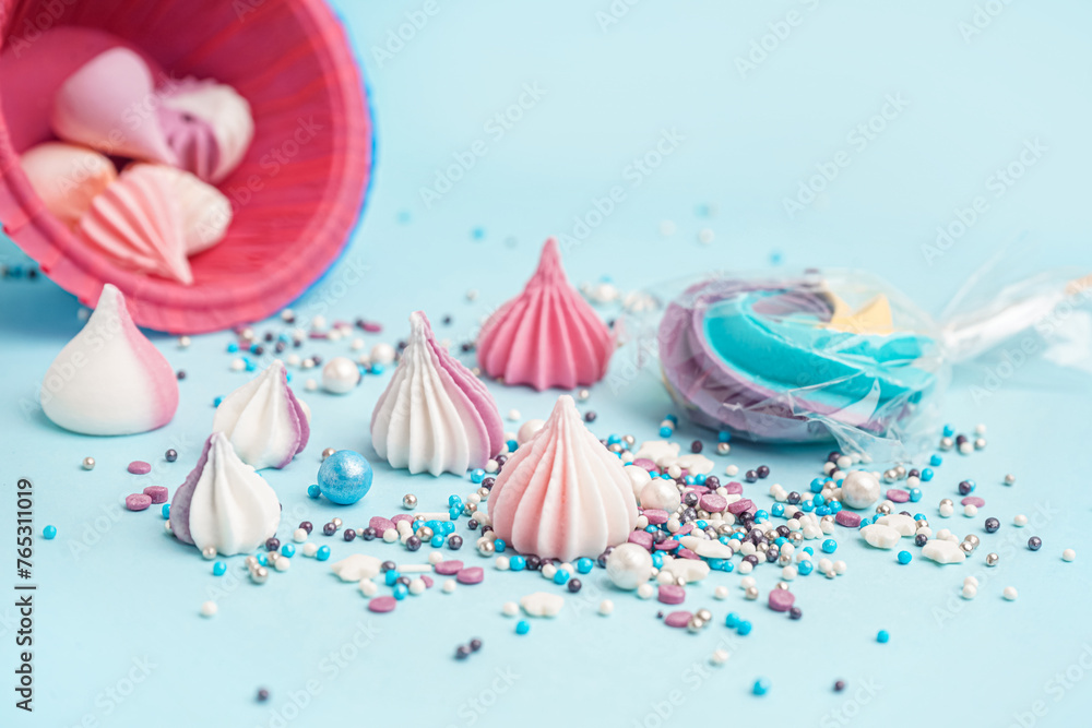 Colorful sprinkles with sweets scattered on blue background
