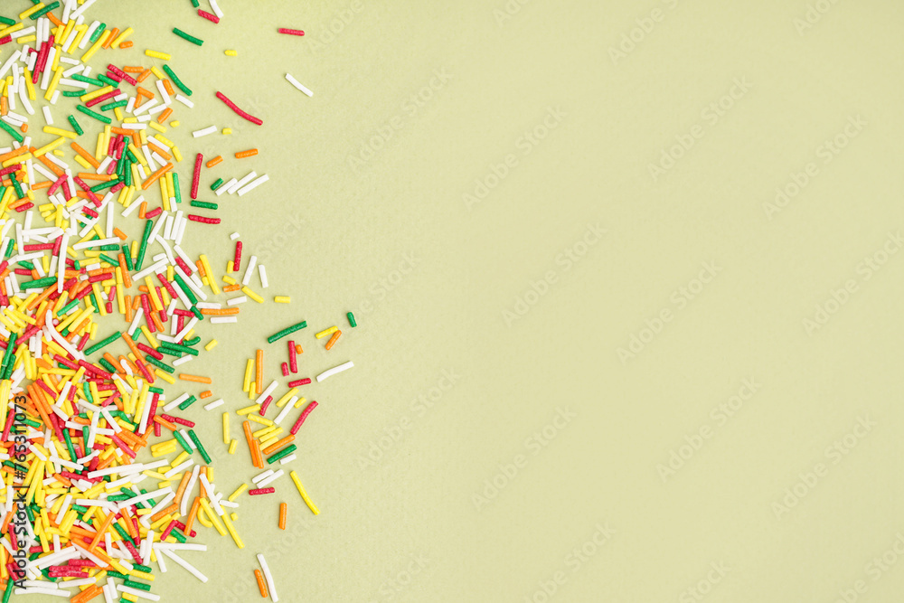 Sweet colorful sprinkles scattered on green background