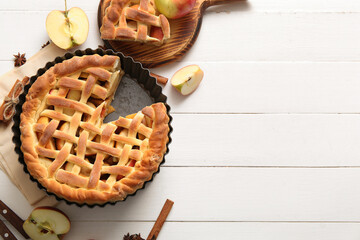 Tasty homemade apple pie with fruits and cinnamon on white wooden background