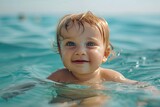 Fototapeta Most - A baby with blue eyes is swimming in seawater.