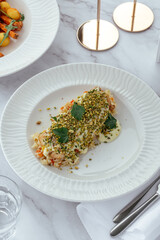 Sticker - fried salmon fillet with sauce, nuts and vegetables on a plate