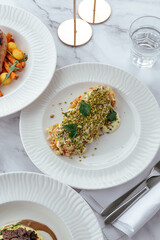 Sticker - fried salmon fillet with sauce, nuts and vegetables on a plate