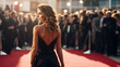 Famous celebrity with beautiful hair and dress, walking and posing, being photographed by crowd of paparazzi photographers at red carpet event. 