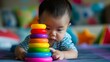 A baby playing with a set of stacking rings, concentrating intently as they try to stack them