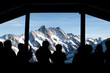 Blick auf die Bergwelt: Silhouetten von Menschen am Panoramafenster
