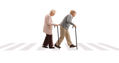 Poster - Full length profile shot of an elderly man and an elderly woman with canes walking at a pedestrian crossing